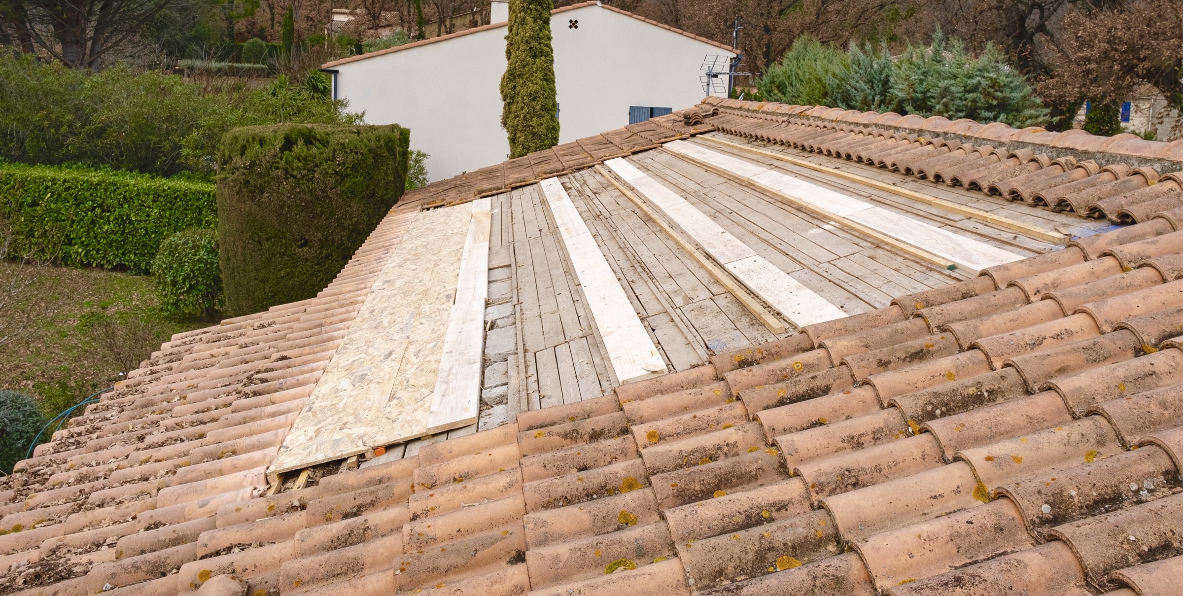 Vue d’une toiture partiellement détuillée montrant le platelage en bois et les liteaux posés, préparation avant pose solaire.
