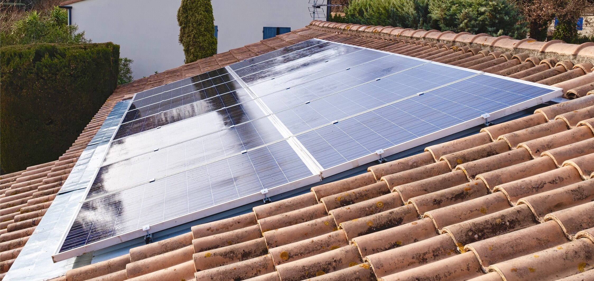 Panneaux photovoltaïques fixés sur un toit en tuiles, surface brillante et réflexion, installation résidentielle.